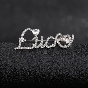 Macro shot of silver 'Lucky' letter brooch with heart and teardrop shaped rhinestones