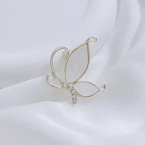 Detailed close-up of butterfly brooch with white mother-of-pearl wings and small crystals