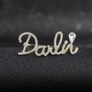 Macro shot of gold letter brooch with pavé rhinestones and a clear teardrop crystal detail