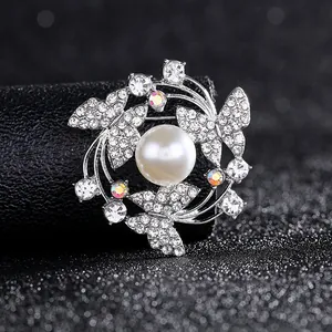 Detailansicht einer silbernen Kranzbrosche mit weißer Perle, Schmetterlingen und Zirkon