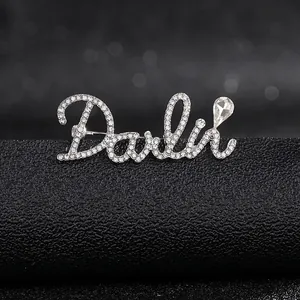 Close-up of Darlie letter brooch with pavé rhinestones and teardrop crystal detail