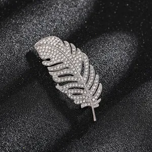 Primer plano de un elegante broche de pluma plateada con diamantes de imitación brillantes