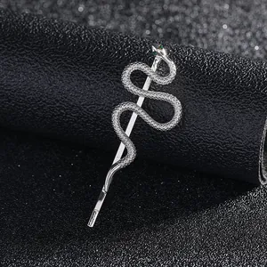 Detail of silver snake hair clip featuring scale texture and green crystal eyes