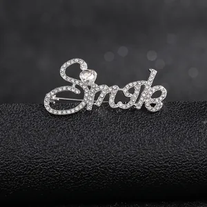 Macro shot of silver letter brooch with pavé rhinestones and a heart-shaped zircon detail
