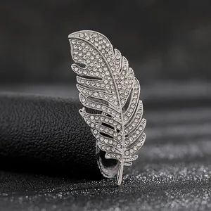 Detalle macro de un broche de pluma plateada con pedrería brillante e incrustaciones