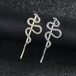 Detail of snake hair clip showing green gemstone eyes and textured metal scales