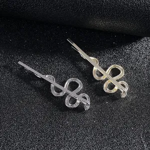 Detail view of wavy snake-shaped hair clips in polished gold and silver alloy finish