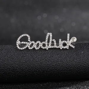 Close-up of Goodluck letter brooch with silver plating and pavé white rhinestones