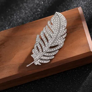 Primer plano de broche de pluma plateada con pedrería brillante engastada de calidad
