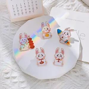 Cinq jolies broches lapin en émail avec motifs de Nouvel An sur support blanc
