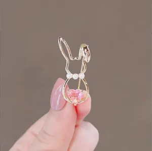Détail d'une broche lapin dorée avec perles blanches et cristal en forme de cœur rose