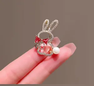 Détail d'une broche lapin avec cristaux blancs, nœud rouge et queue en perle