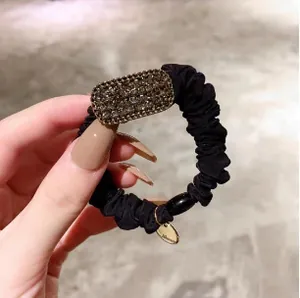 Détail d'un élastique à cheveux noir avec strass brillants et petit pendentif doré