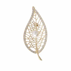 Detalle del broche de hoja dorada con calado intrincado y brillantes cristales blancos