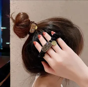 Détail d'une pince à cheveux rectangulaire en cristal sur élastique noir couleur champagne