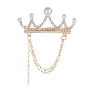 Elegant gold crown brooch featuring white pearls and rhinestone tassels on white background