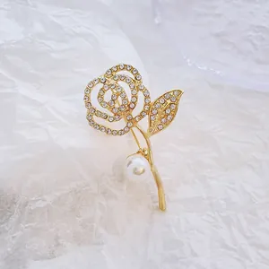 Broche rose dorée élégante avec cristaux et grande perle sur papier texturé blanc