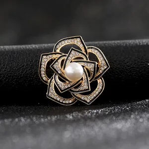 Vista macro de broche de camelia con esmalte negro, brillantes diamantes y perla central