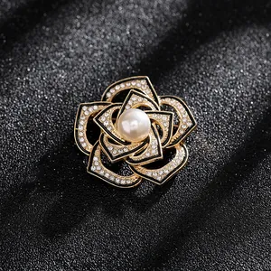 Detalle de broche de camelia con pétalos de esmalte negro y borde de cristales