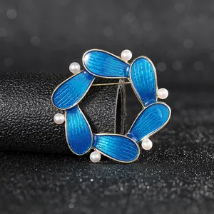 Elegant blue enamel petal circle brooch with white pearls and gold finish on black stand