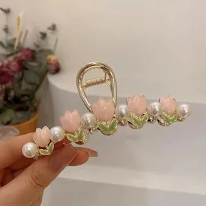 Detailed view of tulip hair claw with pink enamel flowers and white pearls on gold metal