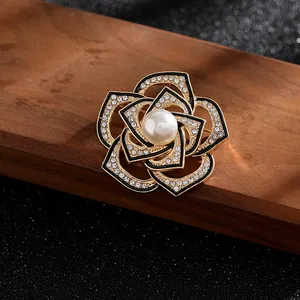 Detalle del broche de camelia con baño de oro, esmalte negro y brillantes piedras strass