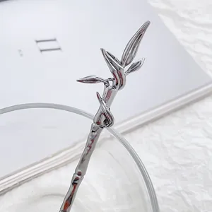 Polished silver bamboo leaf metal stirring spoon shown with elegant glassware
