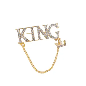Broche dorado con letras KING, diamantes de imitación, corona y cadena de metal