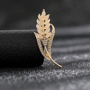 Detalle del broche de espiga dorada con piedras de marfil y brillantes diamantes