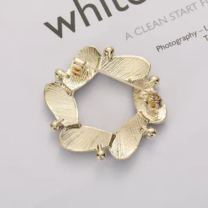 Elegant gold hollow round brooch with blue petal accents and textured metal finish