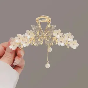 Detail of tulip hair claw with rhinestone butterfly design and elegant pearl tassels
