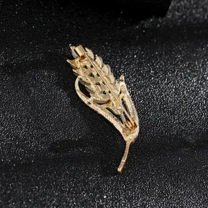 Detalle del reverso del broche de pluma dorada con alfiler de seguridad y cierre