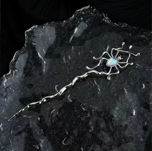 Dettaglio dell'ago per capelli a ragno argento con gemma blu su sfondo ghiacciato