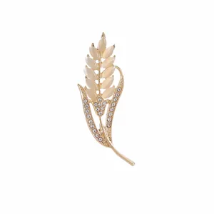 Detalle de broche de espiga con piedras de ópalo crema y micro cristales blancos