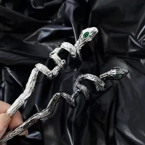 Macro detail of alloy snake hair pins with green gemstone eyes and textured metal finish