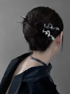 Detailed view of elegant silver snake hair pins with green gemstone eyes on hair