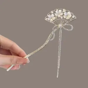 Détail de l'épingle à cheveux en éventail argenté avec fleurs en nacre et glands brillants