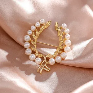 Primer plano de broche floral dorado con perlas blancas sobre fondo de seda champán