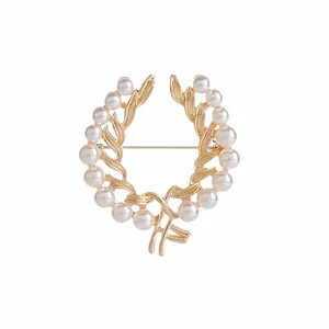 Detalle de broche en forma de corona con perlas blancas y acabado de metal dorado