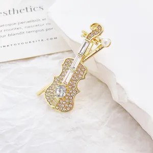 Broche violon exquise avec strass et détail de perle sur fond texturé blanc