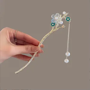 Gros plan détaillé d'un pic à cheveux doré avec fleurs bleues et pampilles de perles