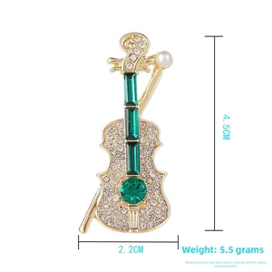 Vue détaillée de la broche violon en cristal vert avec finition dorée et perle