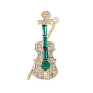 Broche violon dorée avec pierres précieuses vertes, strass brillants et perle blanche