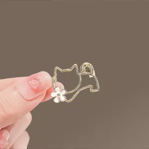 Primer plano de una pinza para el pelo dorada con forma de gato y una pequeña flor blanca