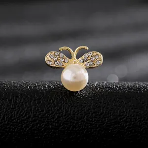 Macro de un broche de abeja con perla blanca y alas brillantes de pedrería dorada
