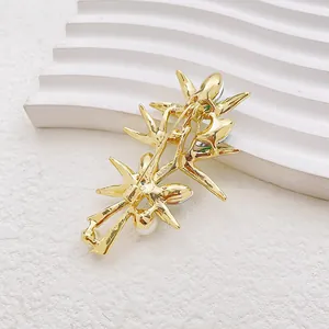 Broche feuille de bambou dorée avec perles blanches et cristaux sur support blanc