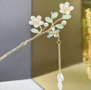 Détail du pic à cheveux muguet avec pétales en nacre et pompon doré