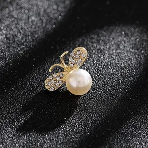 Primer plano de un broche de abeja dorado con perla blanca y alas de cristal brillante
