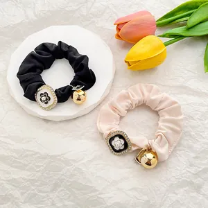 Satin camellia hair scrunchies set with crystal buckle and gold charms on display