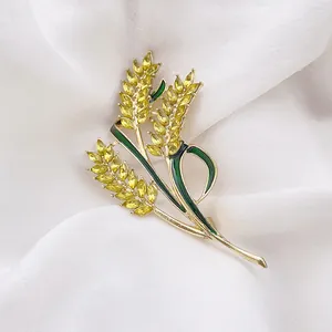 Exquisite golden wheat brooch with yellow crystals and green enamel details on silk fabric